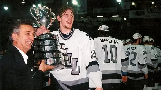 One of the owners, Gilles Sauvé, poses proudly with giant defenseman Colin White.